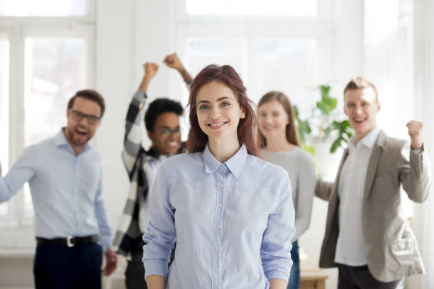 portrait of successful female employee with excited colleagues at back - onboard camera imagens e fotografias de stock
