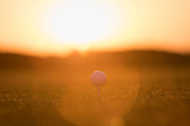 Caucasian mid adult couple enjoying a relaxed walk across a sunlit golf fairway, surrounded by lush greenery and open skies, during a pleasant afternoon. Their leisurely pace reflects a joyful and serene outdoor experience.