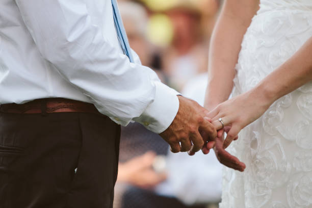 boda pareja explotación manos y poniendo el anillo en el dedo - foto de stock
