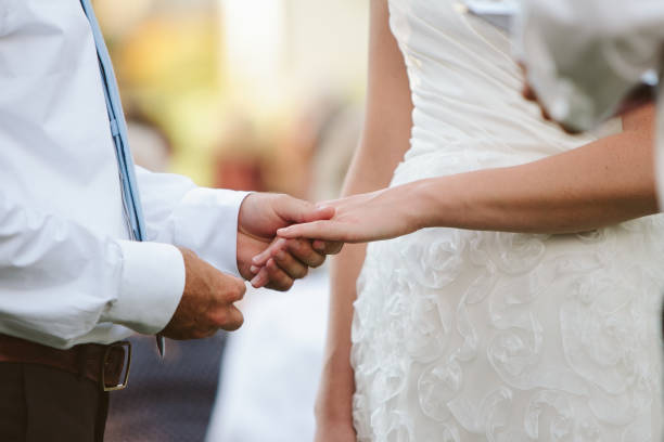 boda pareja explotación manos y poniendo el anillo en el dedo - foto de stock