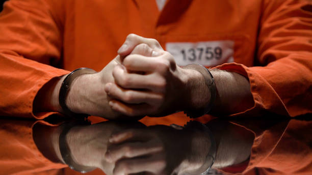 Prisoner in handcuffs clenching fists, denying quilt, interrogation room Prisoner in handcuffs clenching fists, denying quilt, interrogation room detainee stock pictures, royalty-free photos & images