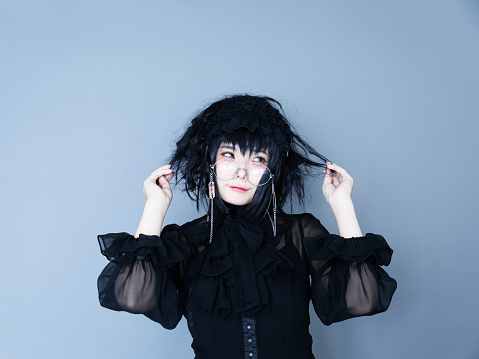 Portrait of Japanese young woman wearing black gothic dress. Looks like Harajuku, Tokyo style. Studio shot.