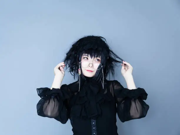 Portrait of Japanese young woman wearing black gothic dress. Looks like Harajuku, Tokyo style. Studio shot.