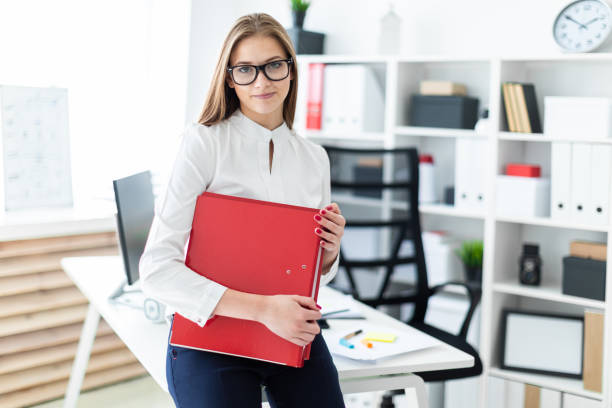 istock A young girl stands near a computer Desk and holds a folder with documents 1091534088