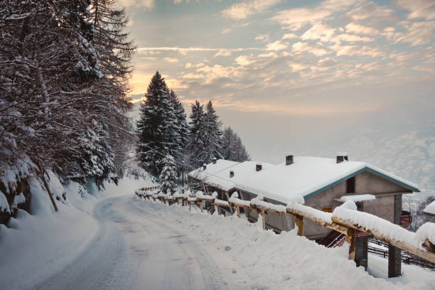 droga pokryta śniegiem z domami ze wschodem słońca - footpath european alps fence woods zdjęcia i obrazy z banku zdjęć