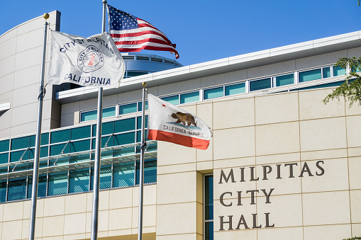 April 30, 2017 Milpitas/CA/USA - The City Hall Building on a sunny spring day; the City of Milpitas, USA and the State of California flags blowing in the wind
