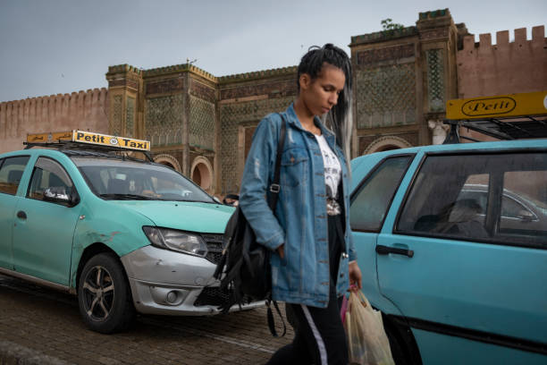 Bab El Mansour in Meknes, Morocco Meknes, Morocco - May 19, 2018: A Moroccan woman walks in Place El Hedim past a line of taxis waiting across the street from the famous gate called Bab El Mansour. It was completed by Moulay Ismail"u2019s son, Moulay Abdallah, in 1732. meknes stock pictures, royalty-free photos & images