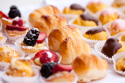 Baked meringue roll with red berries on a round plate, white background