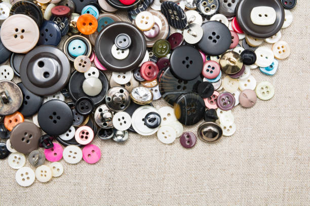 un sacco di bottoni da cucire colorati di diversi colori di metallo e plastica su tessuto naturale leggero di lino - plastic hole heap close up foto e immagini stock