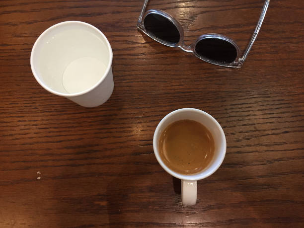 coffee, water cup and sunglasses on wood table top at coffee shop