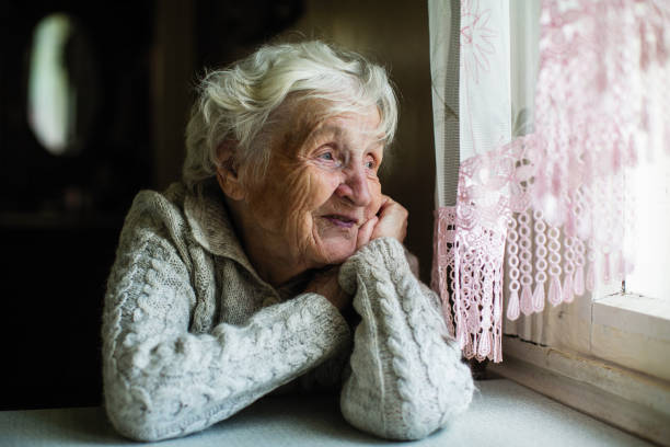 istock Gray-haired elderly woman looks out the window. 1091580646