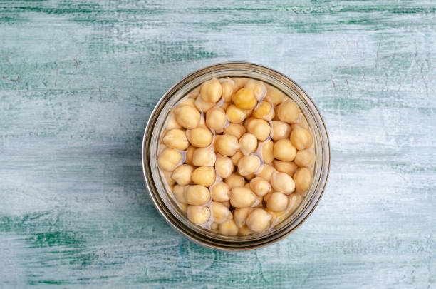 Canned chickpeas in a glass jar Canned chickpeas in a glass jar on a wooden background. Selective focus. chick pea stock pictures, royalty-free photos & images