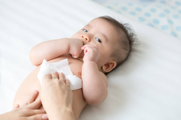 maman nettoyer et essuyer bébé corps de tissu humide quand changer les langes ou couches et l’essuyage des mains ou visage ou jambes, hygiène personnelle pour la mère et l’enfant en bas âge kid avec wet wipes concept papier - rubbing photos et images de collection