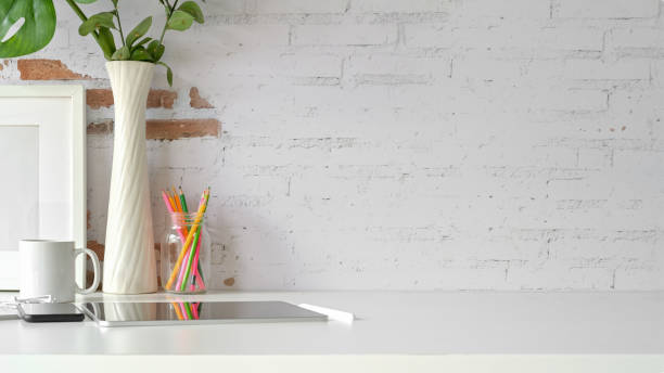 istock Front view of workplace, copy space, tablet, mockup poster on loft workspace white table. 1091627096