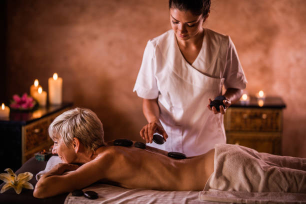 リラックスした年配の女性がスパでホットス トーン療法を持っていること。 - lastone therapy spa treatment massaging massage therapist ストックフォトと画像