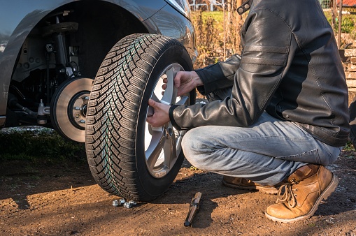 Young man is changing summer car wheel, tire before winter