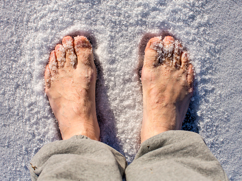 Men's bare feet in the snow in a sunny day