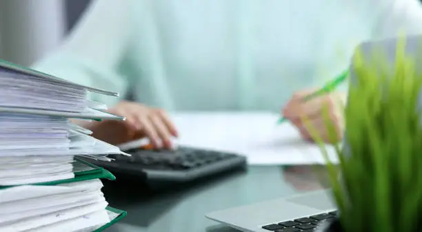Bookkeeper or financial inspector  making report, calculating or checking balance. Audit and tax service concept. Green colored image background.