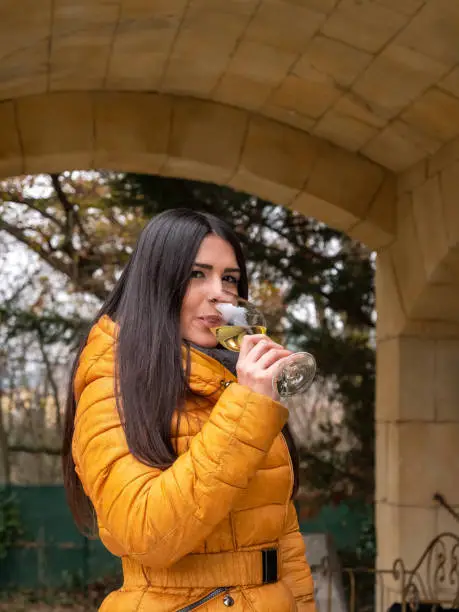 Woman drinking white wine outdoors on an autumn day.