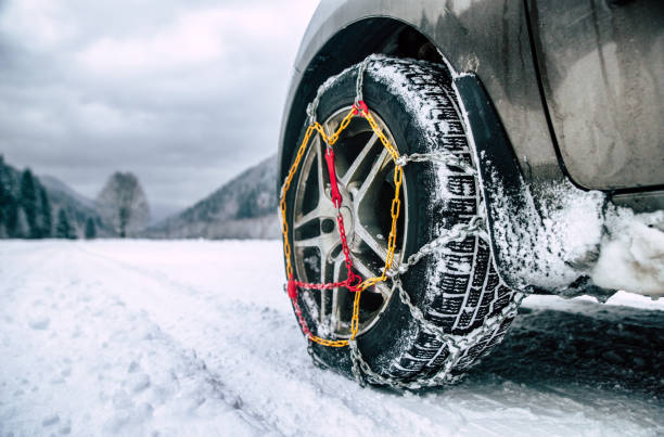 Snow chains on tire at winter road Snow chains on tire. Detail of wheel on wimter road vehicle accessory stock pictures, royalty-free photos & images