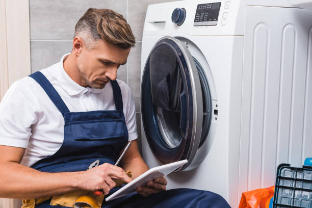 dorosły repairman trzymający śrubokręt i używający cyfrowego tabletu podczas naprawy pralki w łazience - repairing appliance clothes washer repairman zdjęcia i obrazy z banku zdjęć