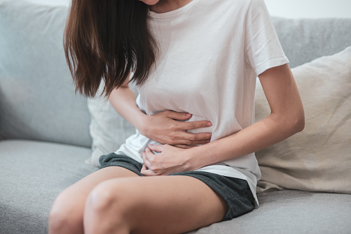 Concepto de salud médica o diaria vida: cerca estómago de joven tiene un dolor de estómago o menstruación sentado en un sofá. photo