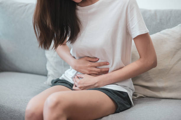 concepto de salud médica o diaria vida: cerca estómago de joven tiene un dolor de estómago o menstruación sentado en un sofá. - menstruación fotografías e imágenes de stock