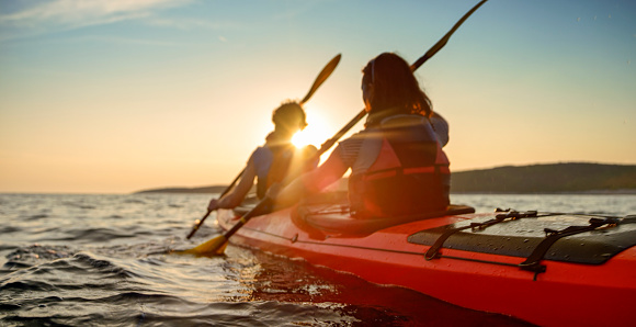 Rear view of male and female kayakers paddling in sea.