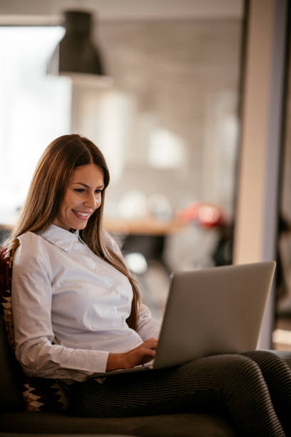 istock Young female using laptop in her living room 1091657758