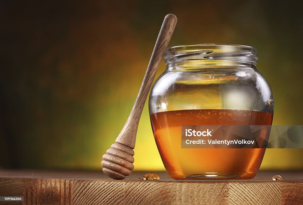 Pot of honey and wooden stick. Pot of honey and wooden stick are on a table. Color Image Stock Photo