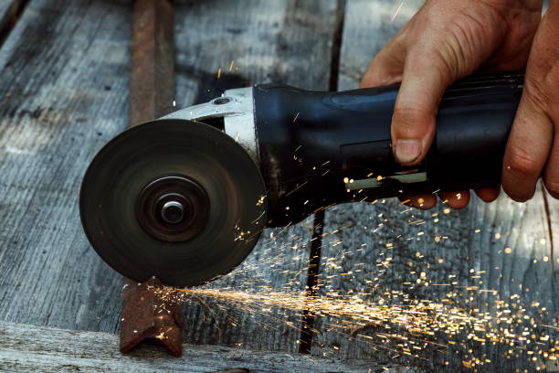 istock a man in working form is working on production, factory physical labor, a man is holding a Bulgarian, he is sawing an iron pipe with a metal disk, sparks are flying, dangerous work 1091664584