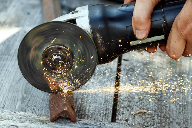 istock a man in working form is working on production, factory physical labor, a man is holding a Bulgarian, he is sawing an iron pipe with a metal disk, sparks are flying, dangerous work 1091664588