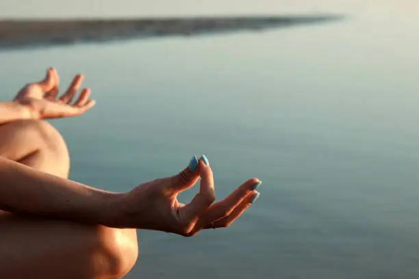 Photo of Young girl silhouette, yoga on nature, on a background of a lake and beautiful sunset. Fresh air, healthy way of life, pleasure, pacification.