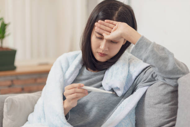 istock Young Asian woman have a cold and high fever while checking body temperature by using digital thermometer. 1091674594