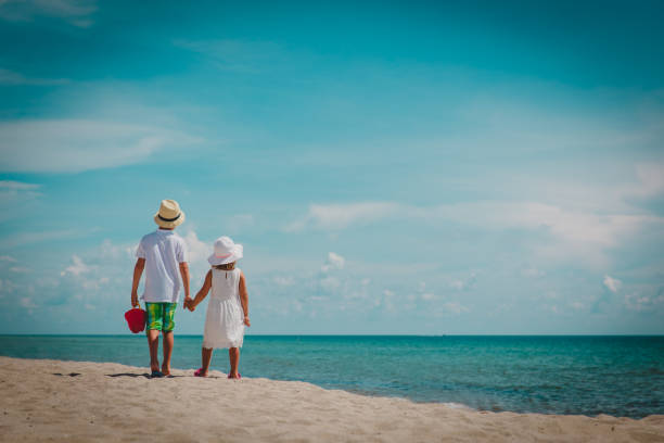 istock little boy and girl walking on beach 1091676376