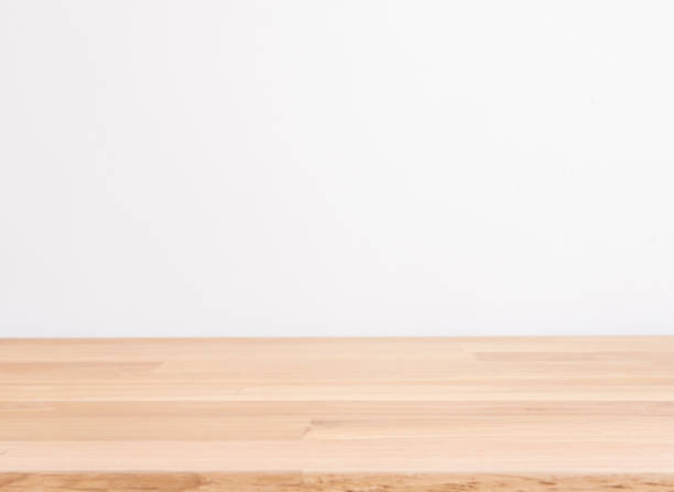 Wooden table with blurred white wall background.