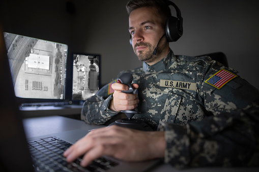 American soldier in headquarter control center initializing drone attack. Modern warfare.