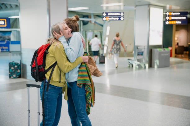 Goodbye Mum, I'll Miss You! Young woman is giving her mother an emotional cuddle in the airport terminal before she leaves to board a flight. airport hug stock pictures, royalty-free photos & images