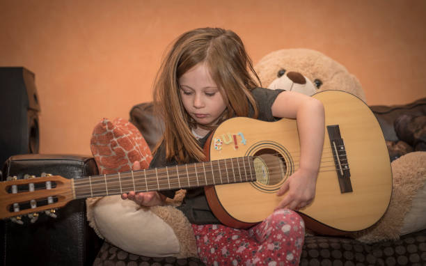 istock Young girl playing guitar at home 1091688710