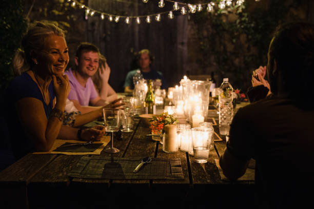 Guests Talking at a Dinner party Close up shot of dinner party guests talking at the table before they eat. garden lights candle stock pictures, royalty-free photos & images