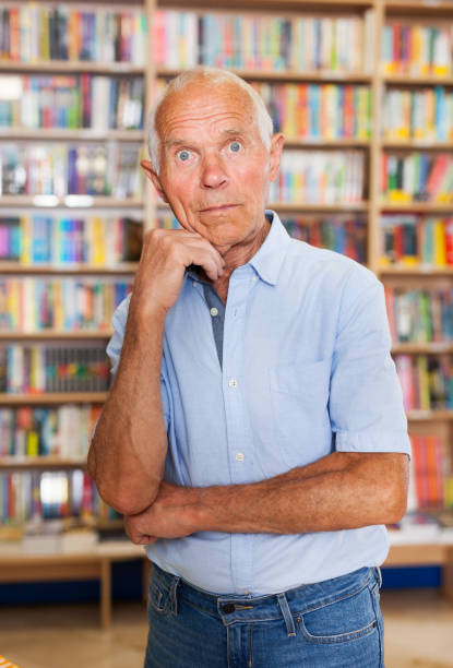 istock Pensive senior man standing in library 1091691038