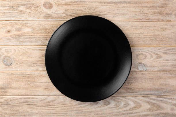 istock Directy above Empty black matte dish for dinner on orange wooden background 1091691234