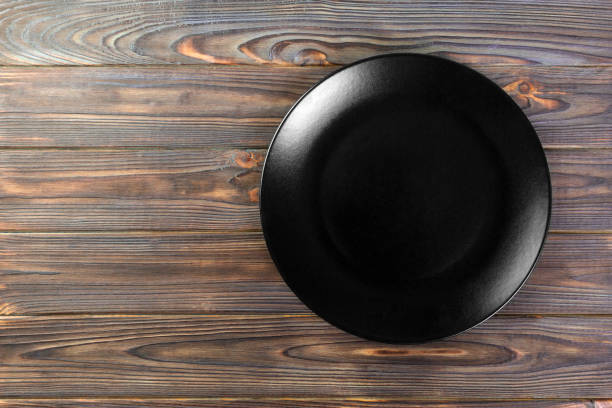 istock Directy above Empty black matte dish for dinner on wooden background with copy space 1091691280