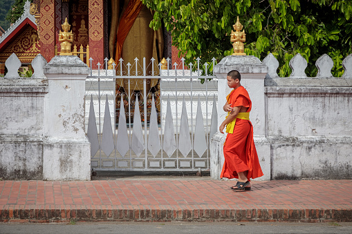 Luang Prabang, Laos - December 7, 2018: Monk walking in the street outside Wat Sensoukaram in Luang Prabang, the former capital of Laos