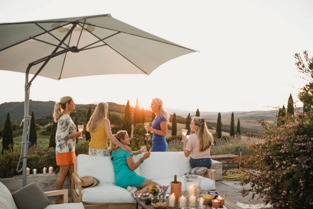 Women Enjoying the Sunset on Holiday Small group of women are watching the sunset from the garden of their villa on holiday. expatriate photos stock pictures, royalty-free photos & images