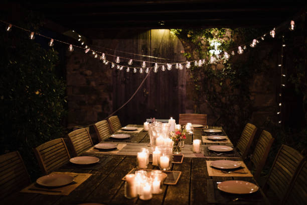 Ready for a Garden Dinner Party Night shot of a dressed garden table illuminated by candles and string lights. outdoor dining photos stock pictures, royalty-free photos & images