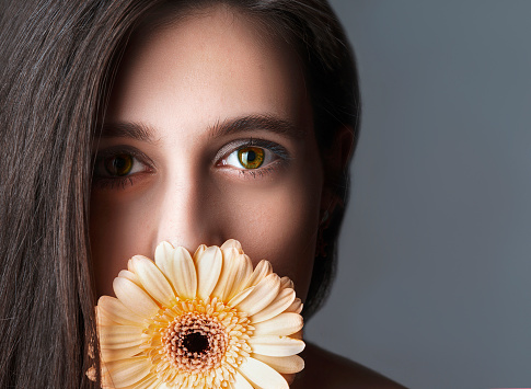 Close up portrait young beautiful woman with yellow flower