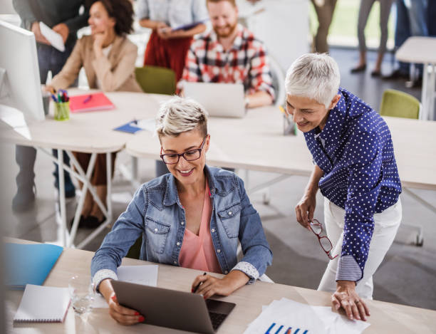 istock Happy businesswomen cooperating while working on computer at corporate office. 1091695244