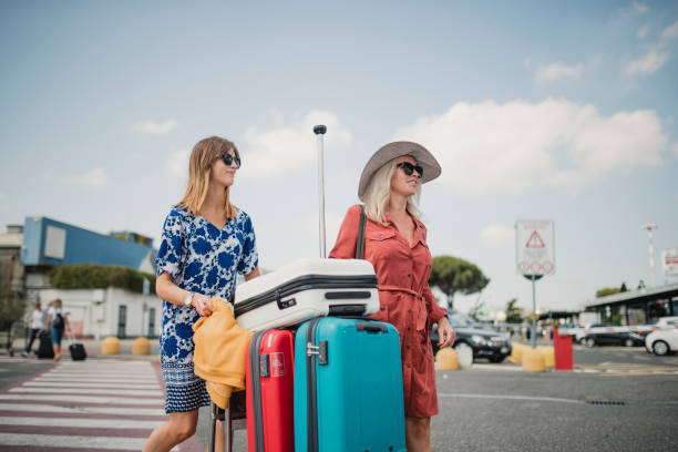 Mum and Daughter On Their Way to the Hotel Mother and daughter are walking trough the airport parking lot after arriving in Pisa. They are pushing a luggage cart and taking in their surroundings. belongings photos stock pictures, royalty-free photos & images