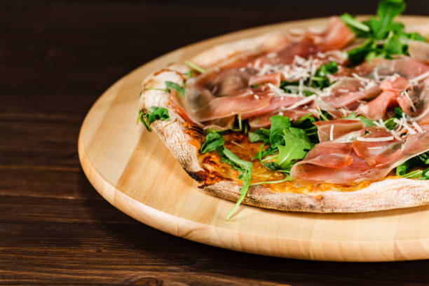 istock Pizza with ham, arugula and cheese on wooden background 1091707562